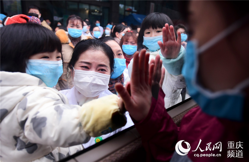 2月11日，重慶市璧山區人民醫院重症醫學科護士王春蘭的5歲女兒和3歲女兒趕到醫院，與媽媽隔窗擊掌為媽媽加油。胡悅建 攝