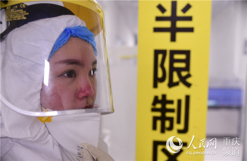 重慶市璧山區人民醫院感染科隔離病房的90后護士匡艷，換好防護服准備走進病房，臉上滿是被口罩勒出的傷痕。胡悅建 攝