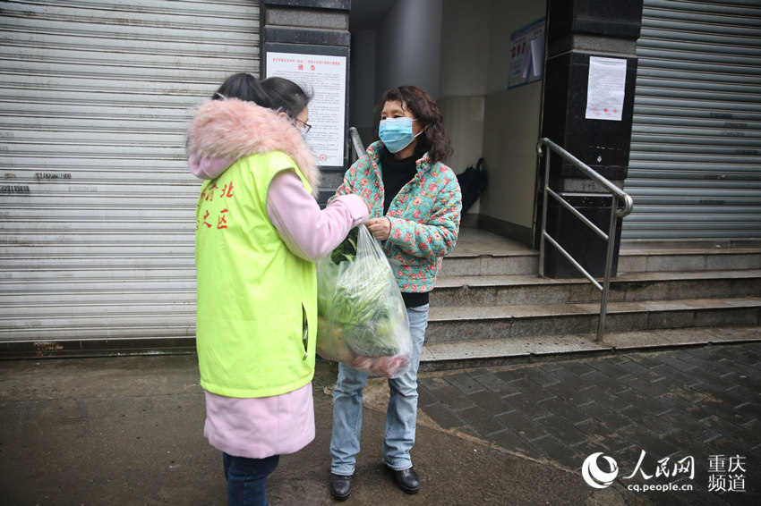 2月15日，幸婭娟在家門口接過社區工作人員手中的菜。劉政寧 攝