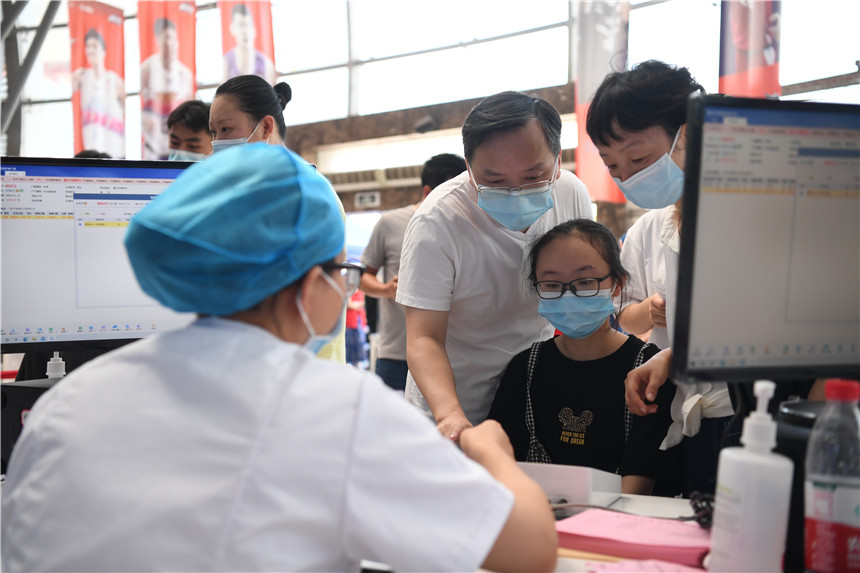 学生在家长的带领下前来接种新冠病毒疫苗。郭旭 摄