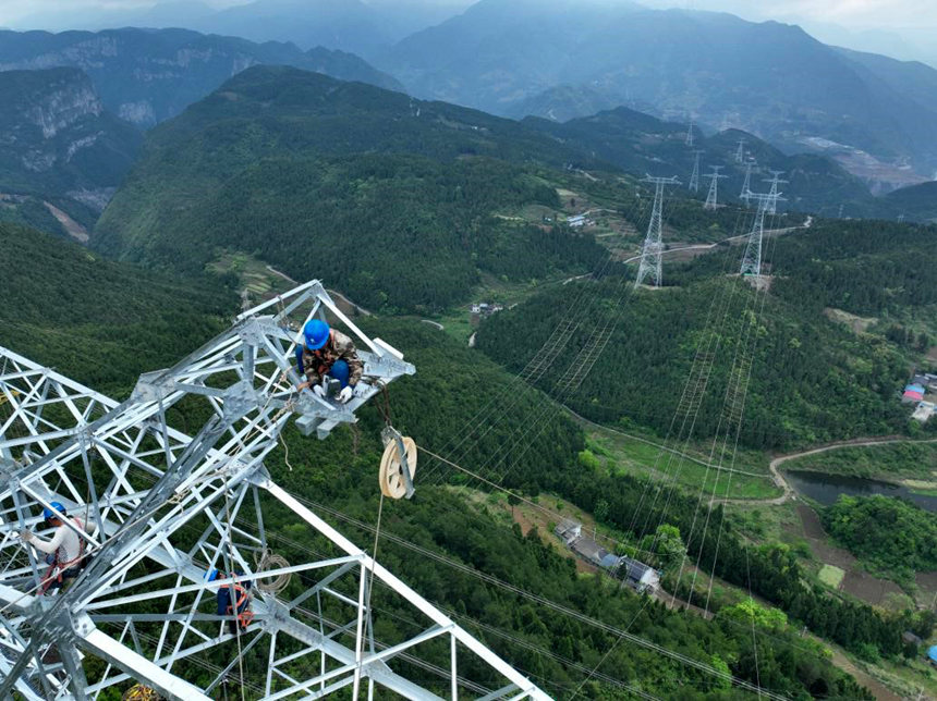 4月29日，國網重慶電力公司員工在逾100米高的特高壓輸電線路上作業。李奕攝