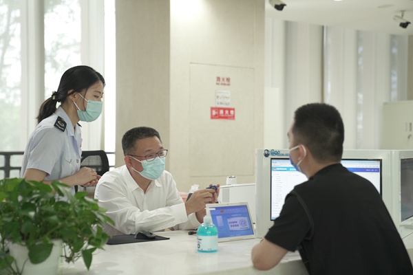 重庆市税务局党委书记、局长许光烈（左二）向重庆佰利恒商贸有限公司办税人员包家鑫（右一）介绍税务Ukey功能。杨俊涛摄