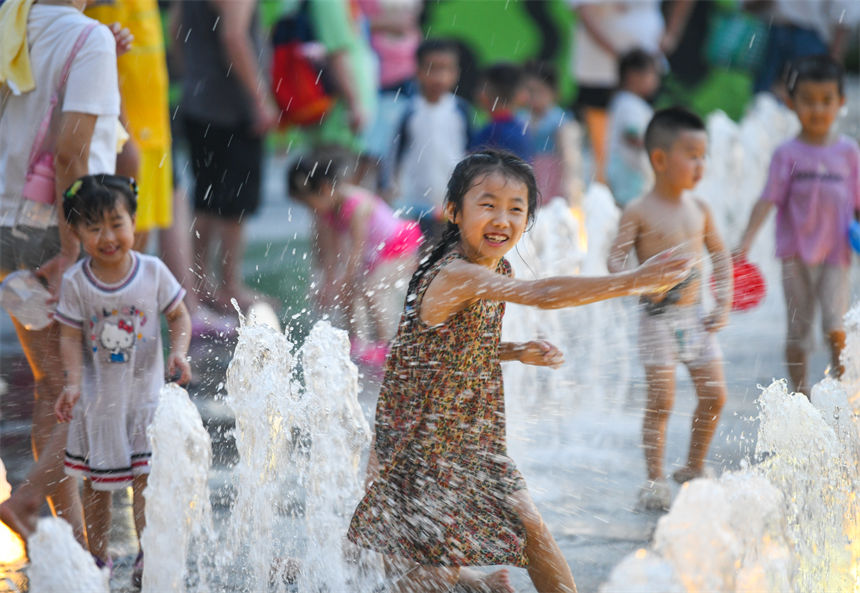重庆连晴高温，小朋友在南滨路喷泉下戏水玩耍享受清凉。郭旭摄