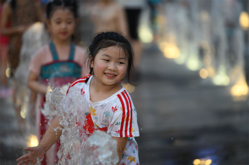 重庆连晴高温，小朋友在南滨路喷泉下戏水玩耍享受清凉。郭旭摄