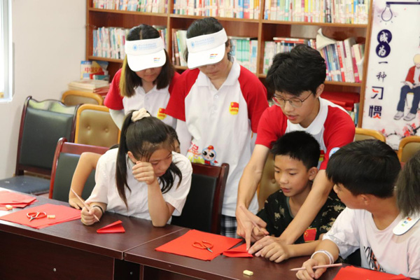 志愿者教村里的孩子剪纸。重庆工程职业技术学院供图