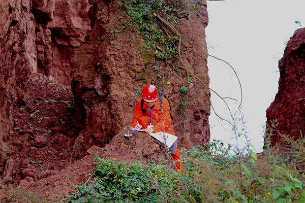 《支撑》。2021年12月8日，技术人员在綦江区郭扶镇垮山村滑坡后缘的危岩下认真填写调查资料，犹如坚固的柱子，支撑着危岩。任良治摄