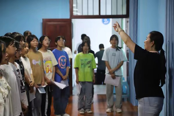 带队教师指导中学生练习齐唱。重庆师范大学供稿图