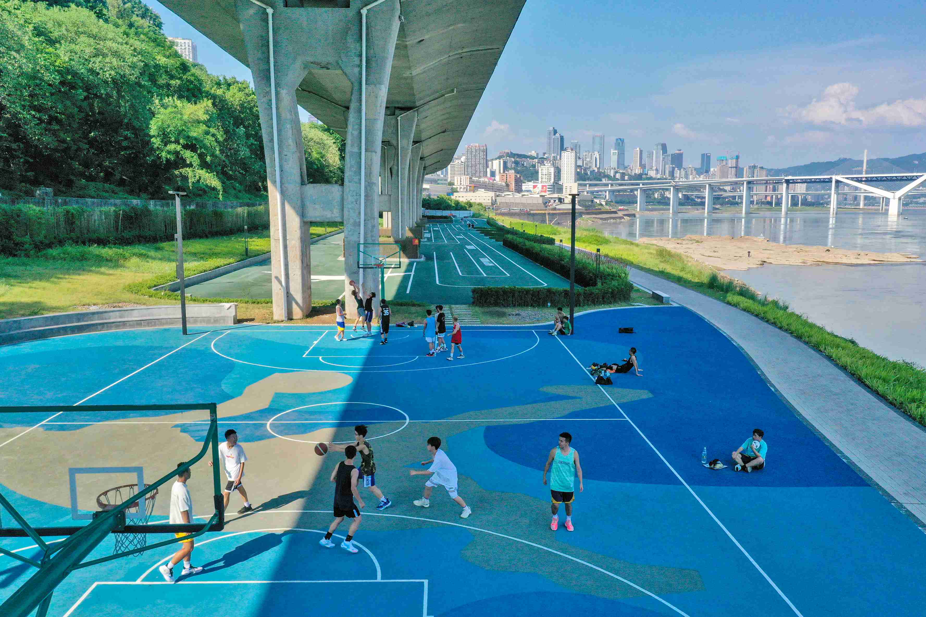 在渝中区黄沙溪大桥下，市民在长江边的篮球场打球。何超摄
