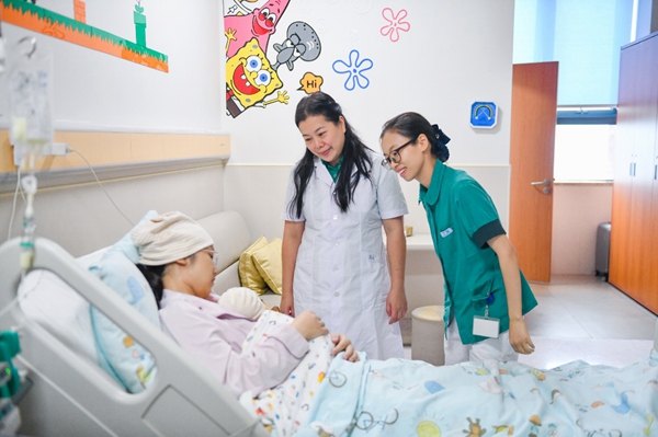 新生儿科副主任韦红教授和责任护士汪燕正在评估新生妈妈护理技能，指导家长做袋鼠抱。邹乐摄
