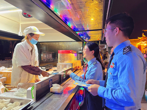 荣昌区税务人员走进荣昌区夏布小镇的夜市宣传税收优惠政策。黄佳摄