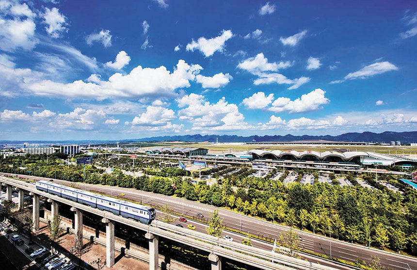 一辆轨道列车从江北国际机场旁驶过。江北国际机场是中西部首个三条跑道、三座航站楼同时运行的机场，迈入全球繁忙机场行列。许可 摄