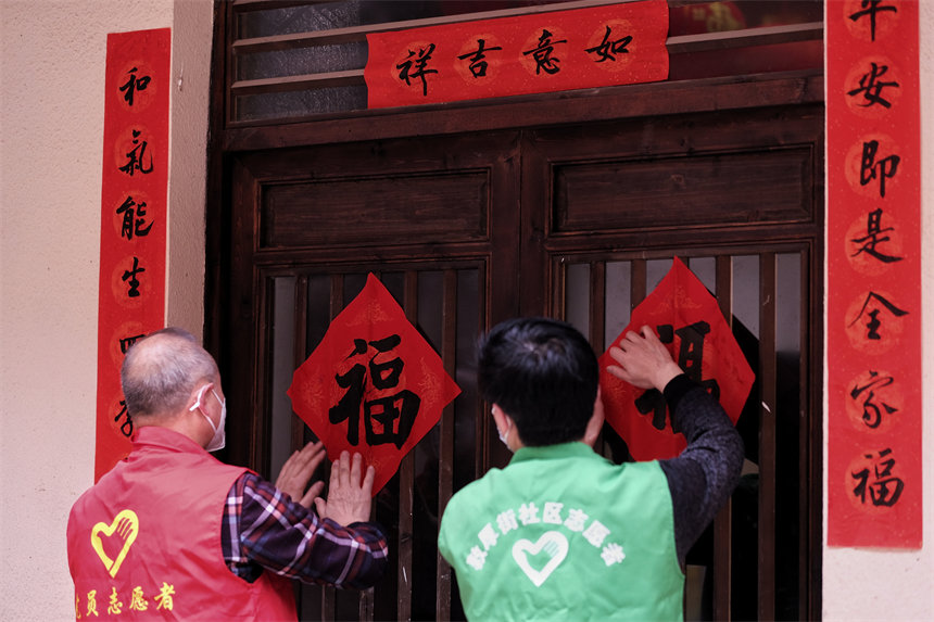 志愿者们正在为黄葛古道敦厚坡段的传统民居贴春联。郭旭摄