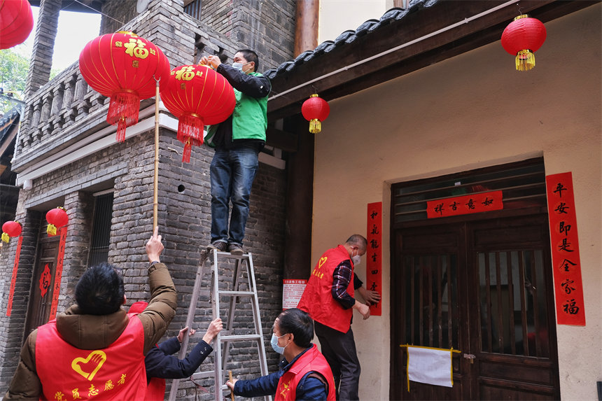 志愿者们正在为黄葛古道敦厚坡段的传统民居悬挂灯笼。郭旭摄