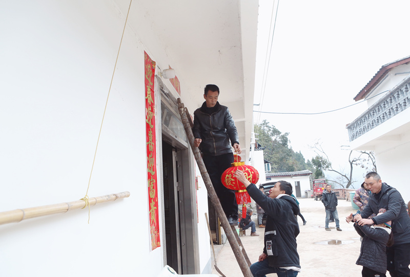 村干部为邓厚国家挂上大红灯笼。卢先庆摄