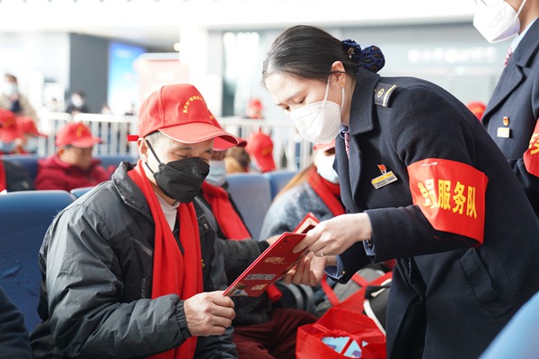重庆西站工作人员为外出务工人员送上春运手册，介绍乘车小知识。魏伟摄