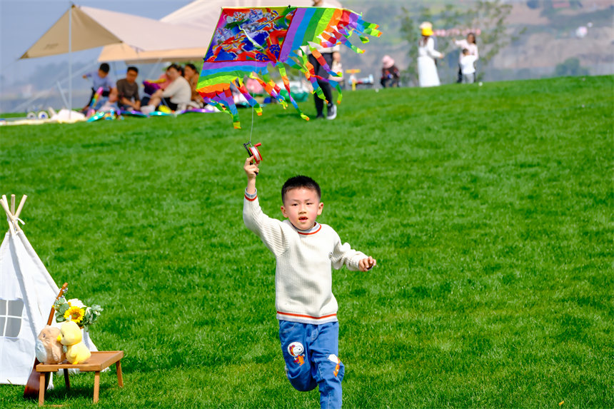 小朋友在草坪上放风筝，乐享春光。郭旭摄