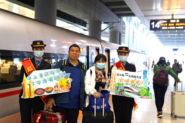 重庆西站“红岩服务站”工作人员手持打卡牌与乘坐G319次列车旅客合影。魏伟摄