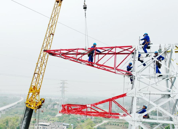 在離地40米高的鐵塔上，國網重慶市區供電公司員工在安裝地線支架部件。李敏攝