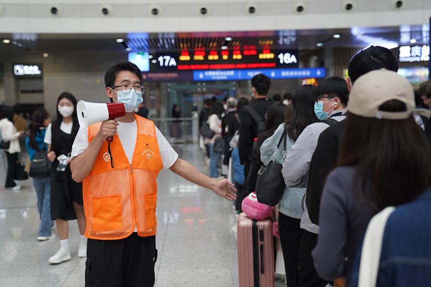 4月29日，重庆北站青年志愿者引导工作人员引导旅客排队检票。汪亮摄