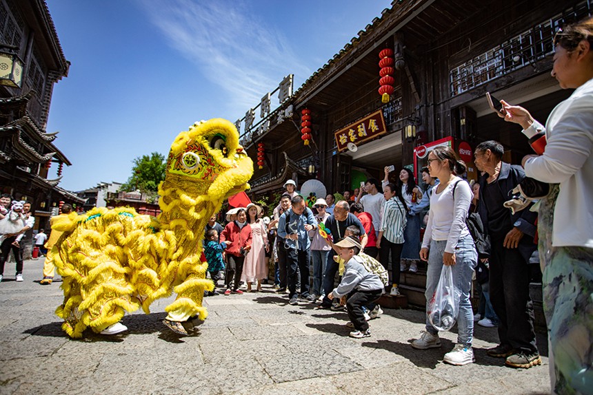 4月30日，秀山县洪安古镇边城景区，游客们在观看舞狮表演。通讯员 胡程 摄/视觉重庆