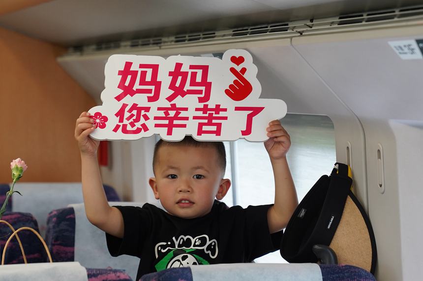 圖16  5月12日，C6409次列車上，小朋友用手持牌向廣大母親送上節日祝福。李文航攝