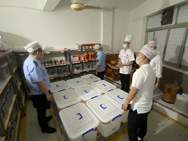 執法人員對學校食堂食品原材料庫房進行檢查。重慶市市場監管局供圖