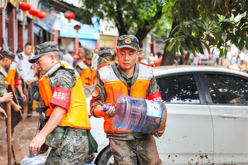 圖為武警官兵幫助受災群眾轉移物資。李東攝