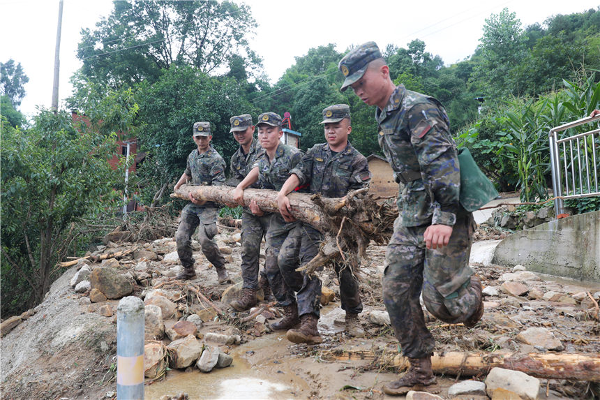 武警官兵清理受灾现场。李东摄