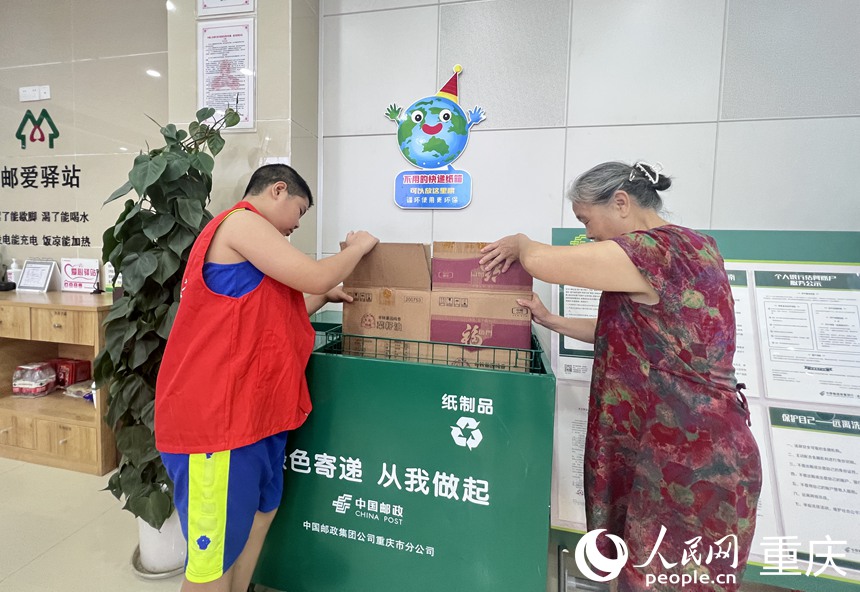 青少年帮市民将纸箱投放进中国邮政的回收箱。人民网记者 胡虹摄