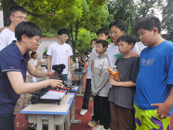 为巫溪县塘坊小学学生讲解写字机器人原理。重庆邮电大学供图