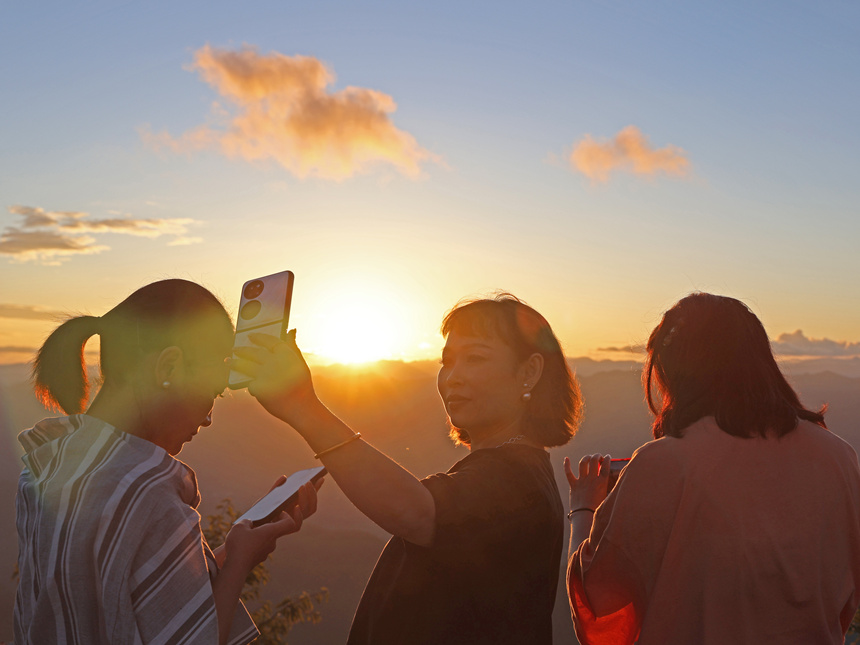 游客在夕阳下拍照留恋，享乡村美景。赵勇摄
