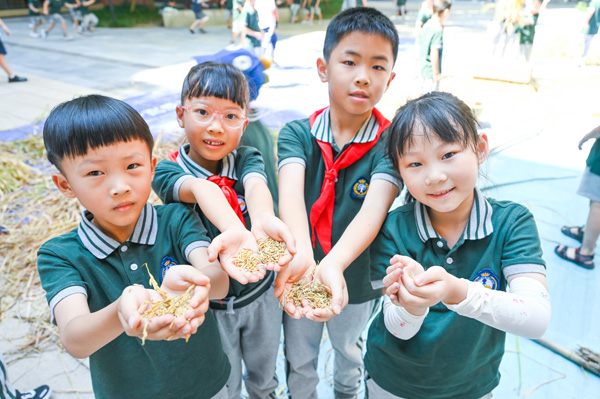 孩子们手捧稻谷，展示劳动成果。两江新区童心小学教育集团供图