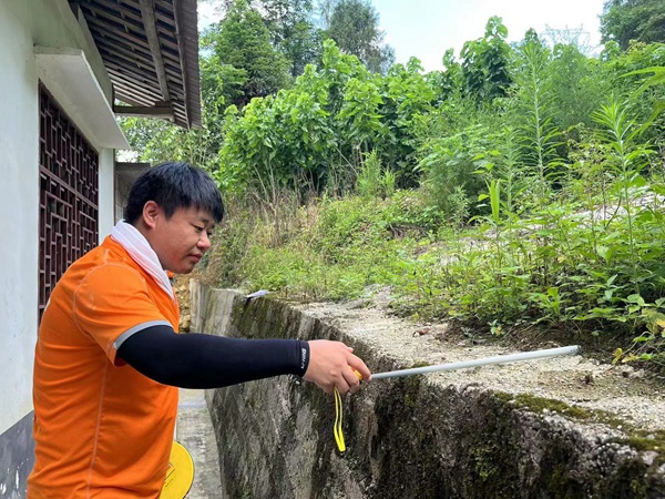 《实测实量》。7月29日，川东南勘察公司驻守地质工程师曹志远在黔江区阿蓬江镇分水村，对陆家河滑坡范围内的居民房屋后边坡已建挡墙的宽度进行实测。王龙贵摄