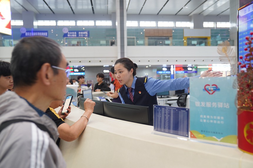 重庆北站“马廉服务台”工作人员引导旅客前往检票口。魏伟摄