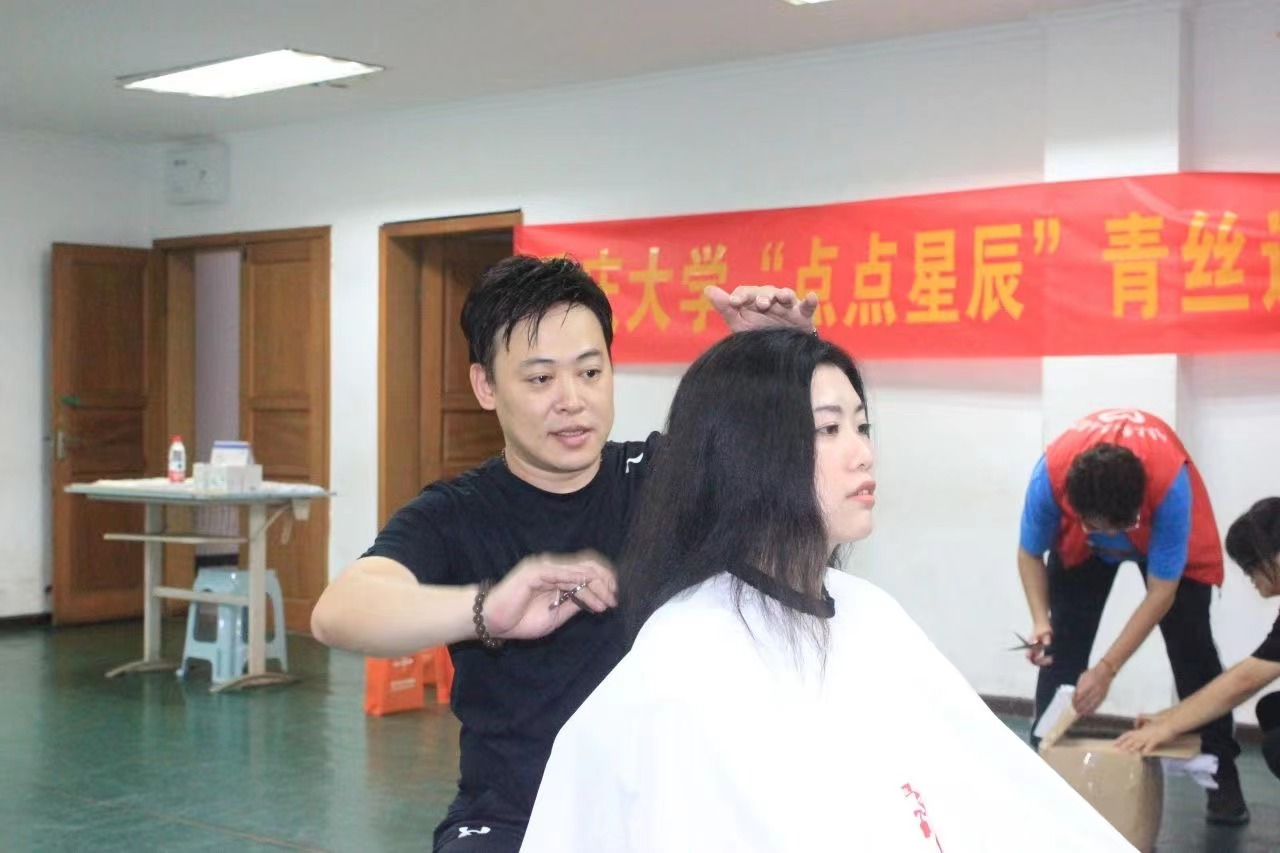 理发师为志愿者剪发。重庆大学供图