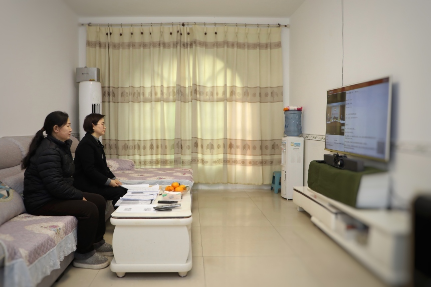 原告刘兴容（左）在家中通过电视机“全渝数智法院TV版”出庭。蹇懿摄