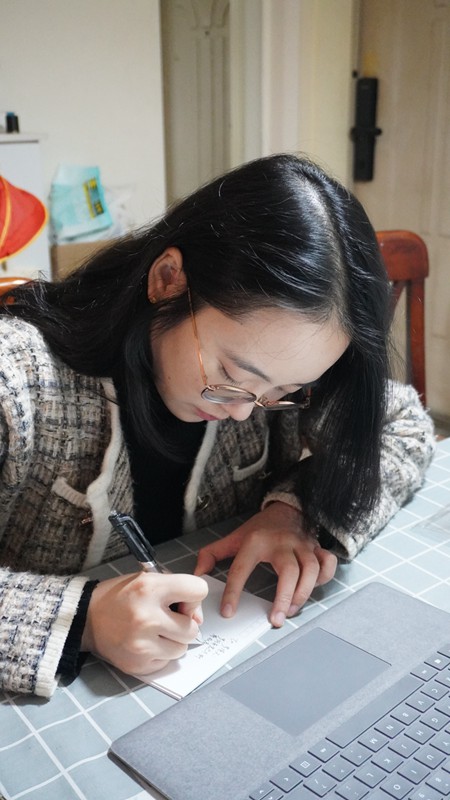 杨茜在家中写明信片（家人拍摄）。西南大学供图