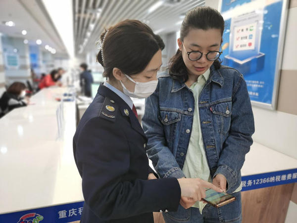 重庆市万盛经开区税务局工作人员辅导市民在手机上办理个税汇算。蒋苹摄