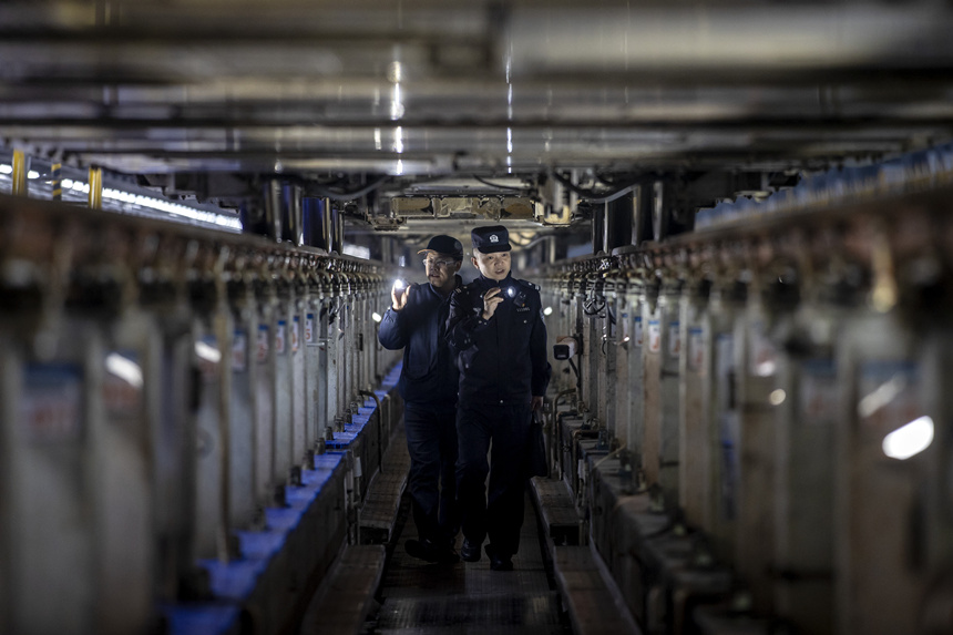 彭聰（右一）在重慶北動車所工作人員的配合下，對檢修庫作業線上的電路阻燃絕緣防護進行檢查。胡勇攝