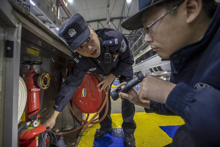 彭聰（左一）在重慶北動車所工作人員的配合下，對檢修庫的消防栓進行檢查。胡勇攝