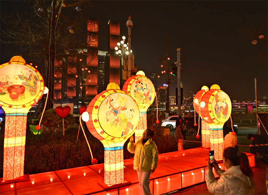 游客在南岸区南滨路钟楼广场赏灯拍照。郭旭摄