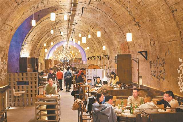 重庆地下之城老火锅，500余米长的防空洞内两侧摆放了208张桌位，宽大而深邃的防空洞，被“千灯万盏”孔明灯点亮。