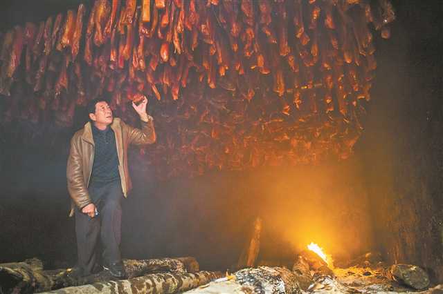 城口老臘肉非物質文化遺產第四代傳承人趙孝春在檢查烘烤的臘肉。（資料照片）記者 謝智強 攝/視覺重慶