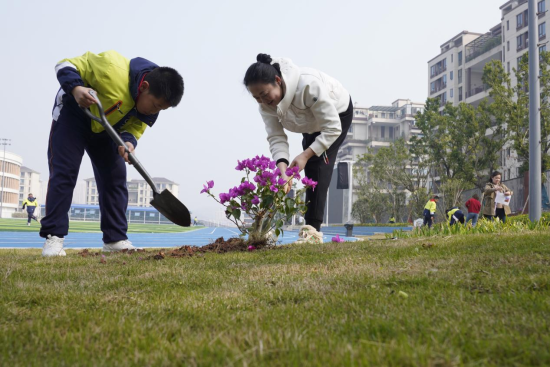 图为学生与家长代表共同植树现场。秦廷富 摄