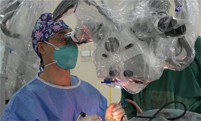 余星醫生在顯微鏡下精細操作切除顱腦腫瘤。