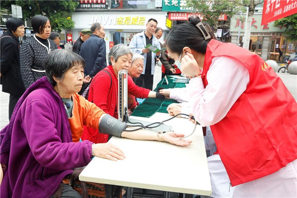 “梁家人”利民医院志愿服务队队员为市民测量血压。谭燕摄