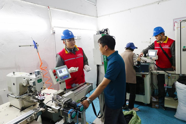 国网重庆黔江供电公司员工在重庆厚德服装加工有限公司生产车间帮助排查用电安全隐患。杨敏摄