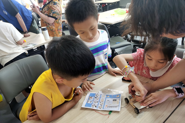 志愿者协助小朋友制作声控小车。西南大学供图