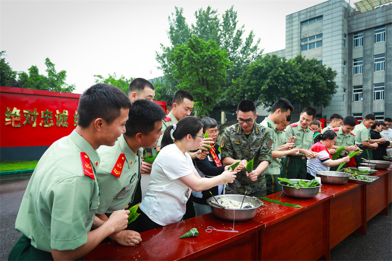驻地热心群众与武警官兵一起包粽子。翁锡鹏摄