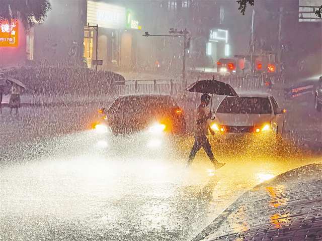 7月13日晚，渝北區獅子坪輕軌站，市民撐傘在暴雨中走過。當晚，主城區出現雷電暴雨天氣。記者 劉力 攝/視覺重慶
